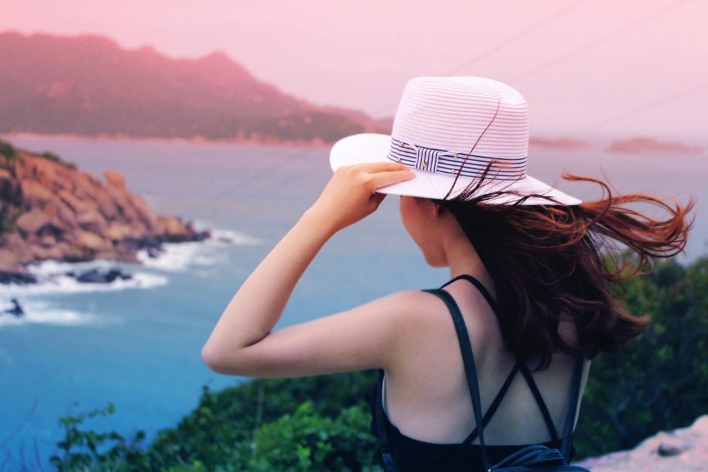 Wman Holding Wricker Shade Hat on Ocean View